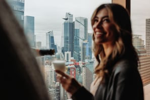 A person holding a drink with a cityscape in the background.