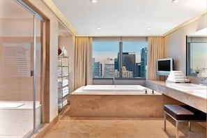 A modern bathroom with a large bathtub, a vanity with a mirror, and a city view.