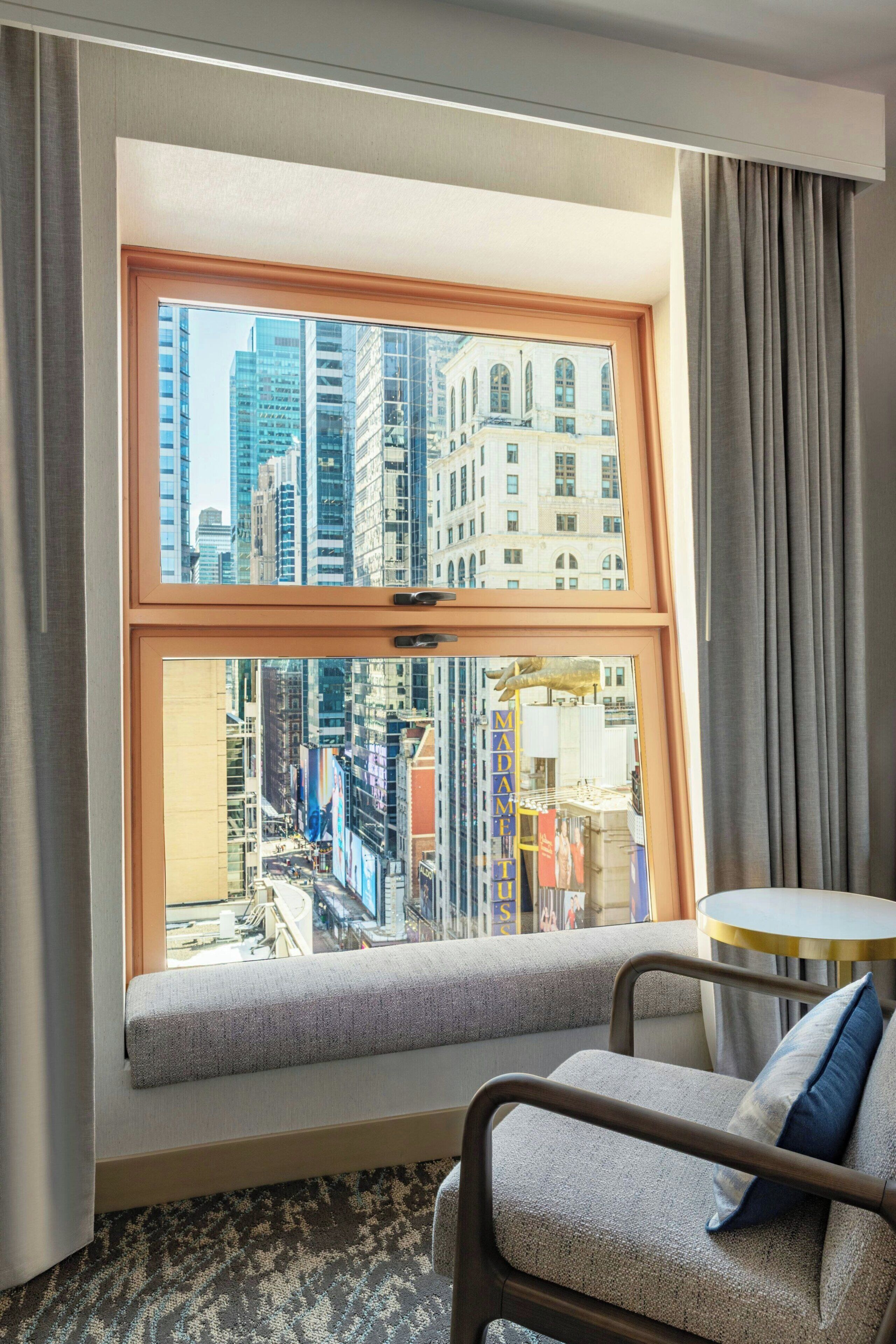 A hotel room with a large window, a sofa, and a small round table.