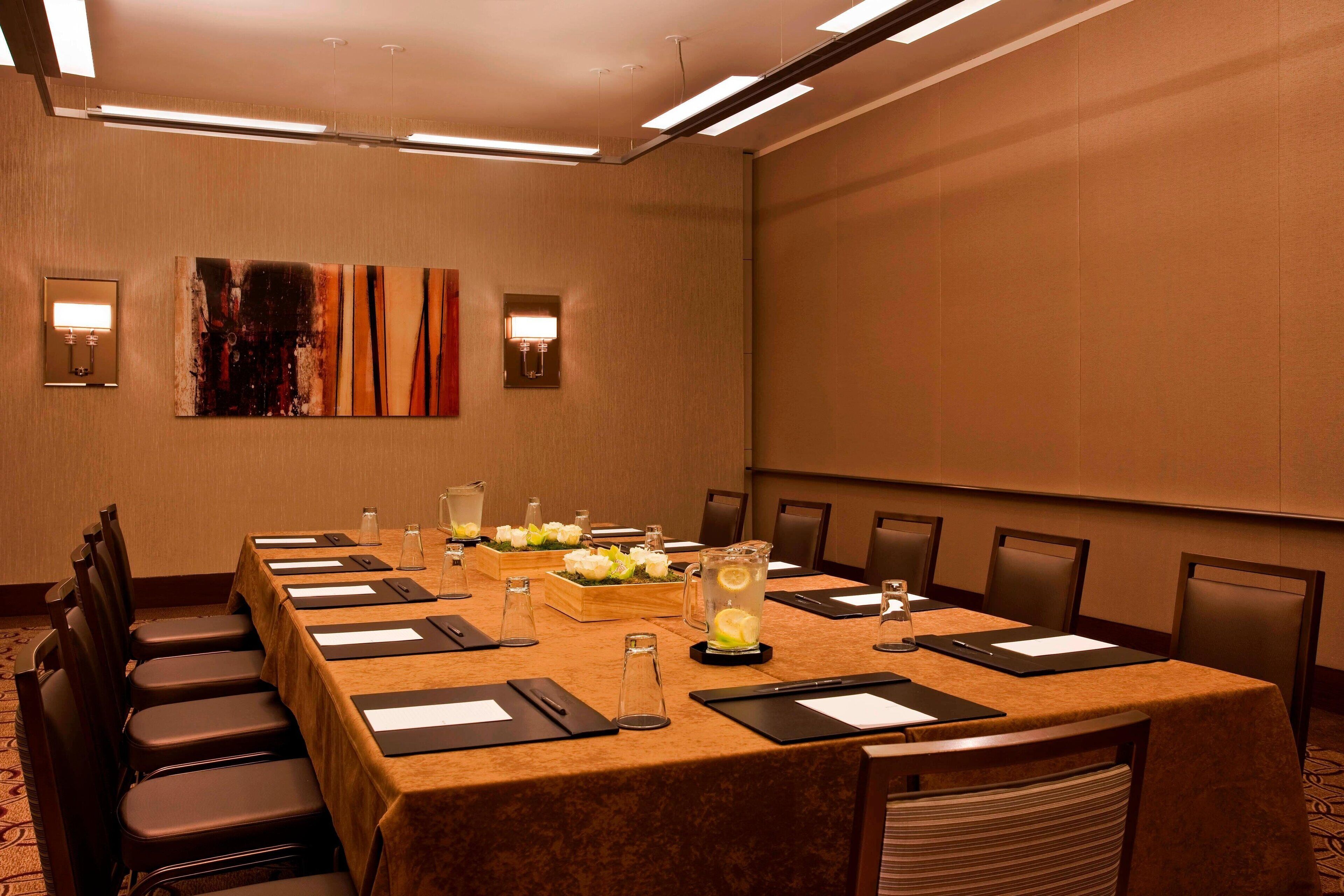 A conference room with a long table, chairs, and a projector screen.