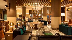 A modern lobby with a central seating area, a bookshelf, and a staircase.