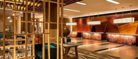 A modern lobby with a reception desk, seating area, and decorative lighting.