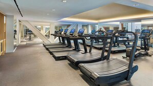 A gym with treadmills, a staircase, and a view of the city.
