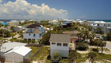 A coastal residential area with houses, some with balconies, and a beach in the background.