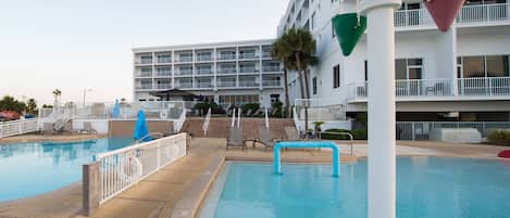 A swimming pool area with a multi-level hotel building in the background.