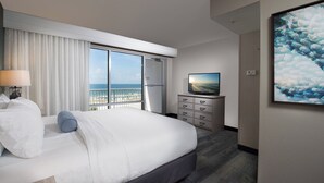 A hotel room with a large bed, a television, a dresser, and a view of the ocean through a sliding door. - SpringHill Suites Pensacola Beach (Pensacola Beach)