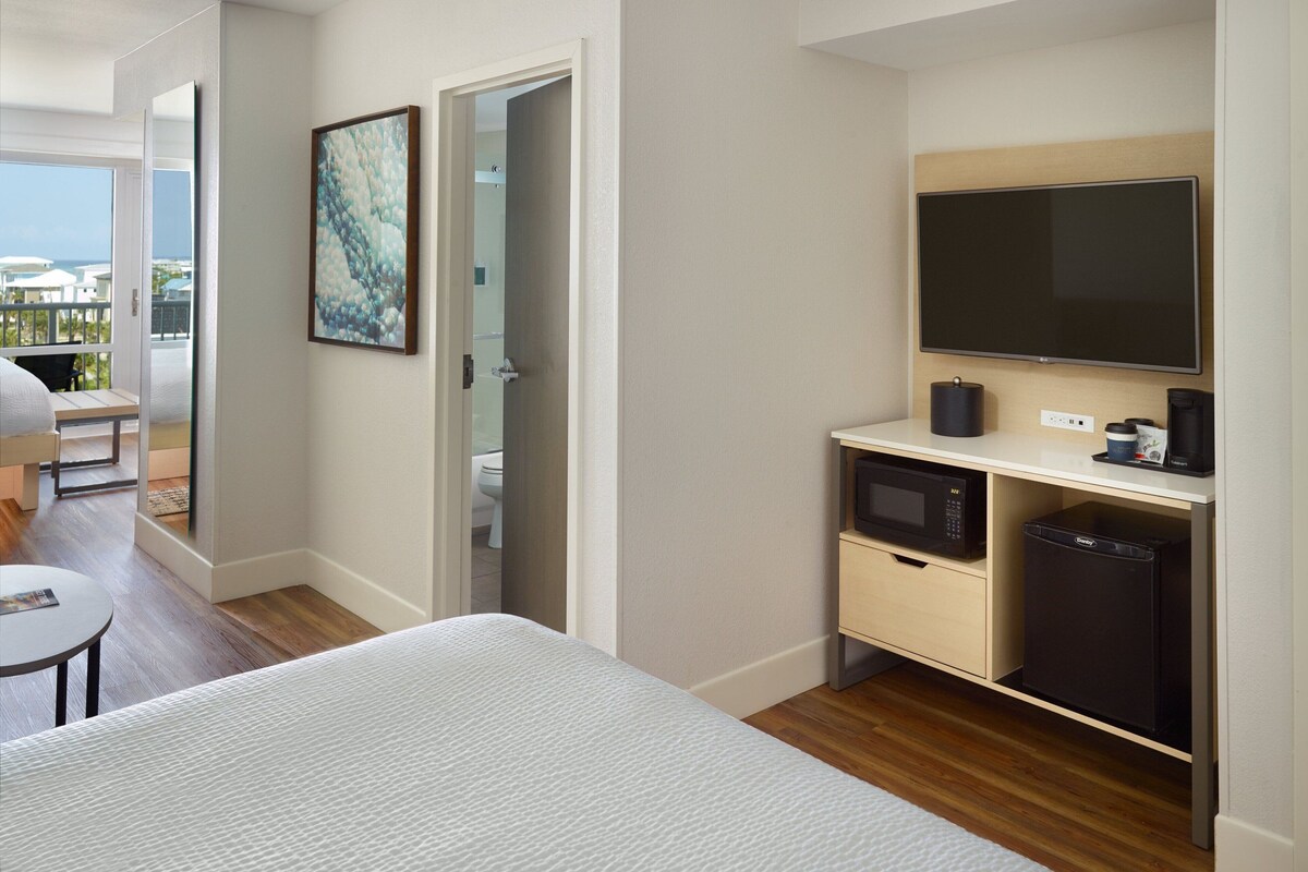 A hotel room with a bed, a small table, a TV, a microwave, and a mini-fridge.