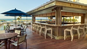 A wooden deck with outdoor seating, a bar area, and a view of the ocean. - SpringHill Suites Pensacola Beach (Pensacola Beach)