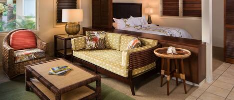 A hotel room with a bed, a sofa, a chair, a small table, and a nightstand.