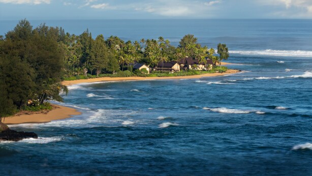Une propriété située sur la côte, avec une plage, une vue sur l’océan et une végétation tropicale.