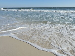 A beach with waves gently lapping onto the shore. - Seawinds Condominiums by Wyndham Vacation Rentals (Gulf Shores)