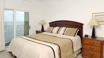 A bedroom with a bed, bedside tables, a nightstand, a window with a view, and a door.
