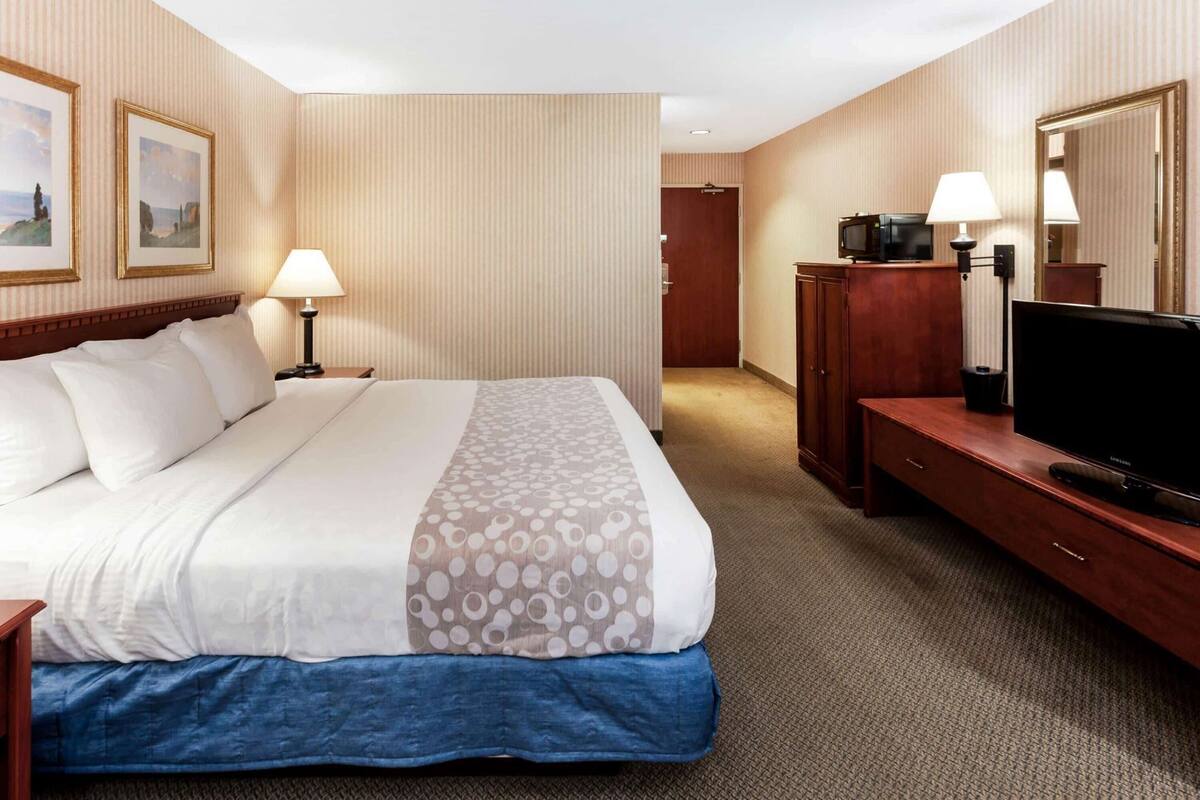 A hotel room with a large bed, a television, a desk, and a wardrobe.