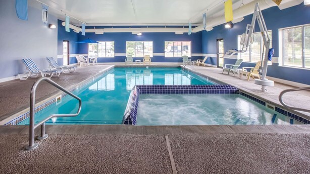 An indoor swimming pool with clear blue water, surrounded by lounge chairs and a lifeguard stand.
