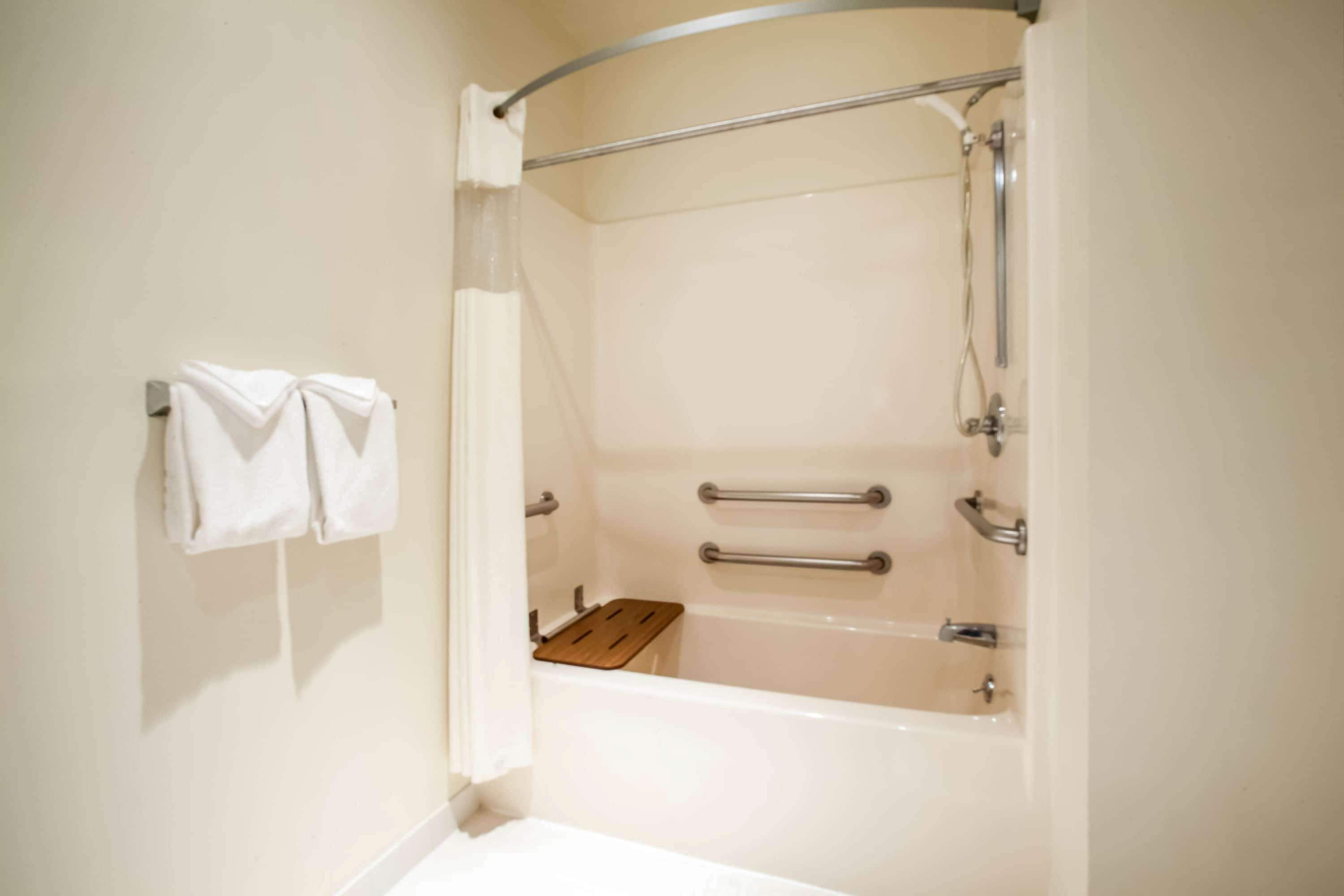 A bathroom with a bathtub, a shower, and a towel rack with two towels.