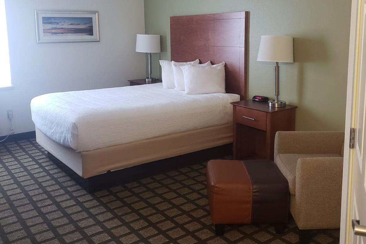 A hotel room with a large bed, two bedside tables with lamps, a small sofa, and a patterned carpet.