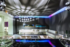 Un interno moderno con un divano bianco, un tavolino in vetro e un soffitto decorato.