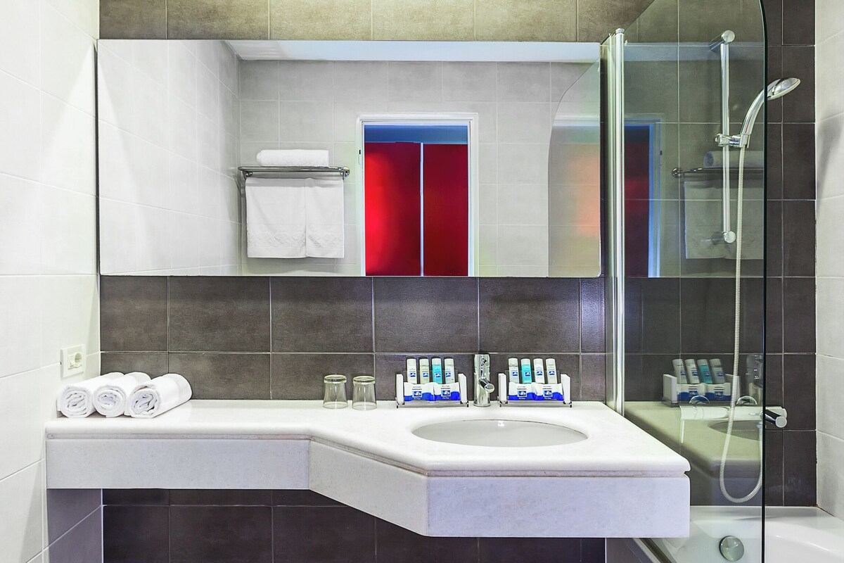 A modern bathroom with a large sink, a glass shower enclosure, and a mirror above the sink.