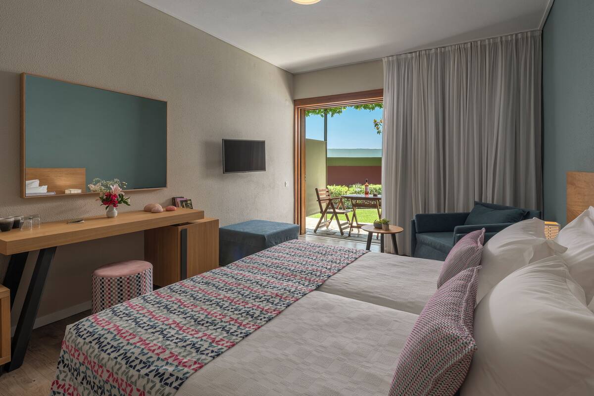 Une chambre d’hôtel équipée d’un lit, d’un bureau, d’une chaise, d’une télévision et offrant une vue sur l’extérieur.