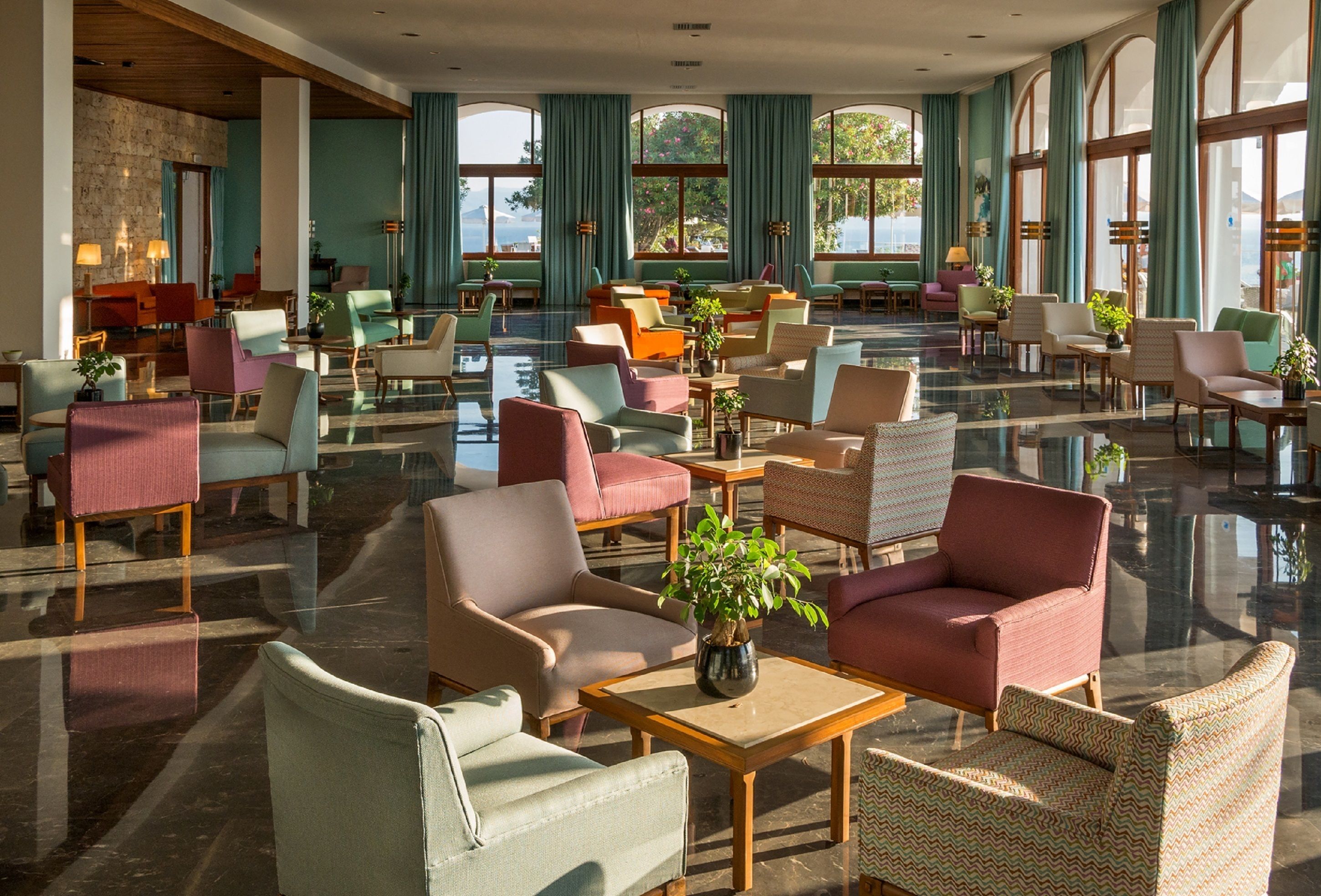 A spacious lobby with multiple seating areas, large windows, and a polished floor. - Skiathos Palace Hotel (Skiathos)