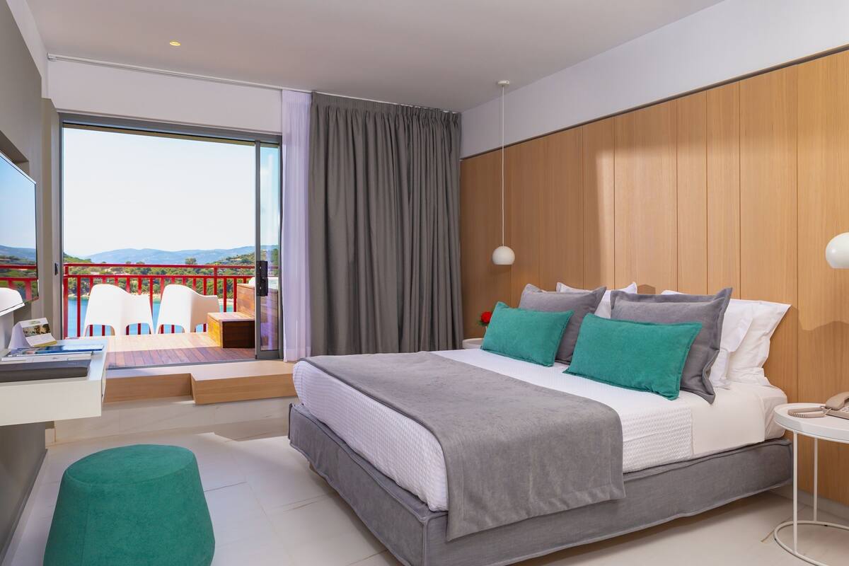 Une chambre moderne avec un grand lit, un bureau et une vue sur un balcon.