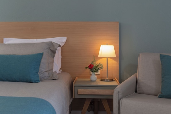 A hotel room with two beds, a nightstand with a lamp, and a chair. - Skiathos Palace Hotel (Skiathos)