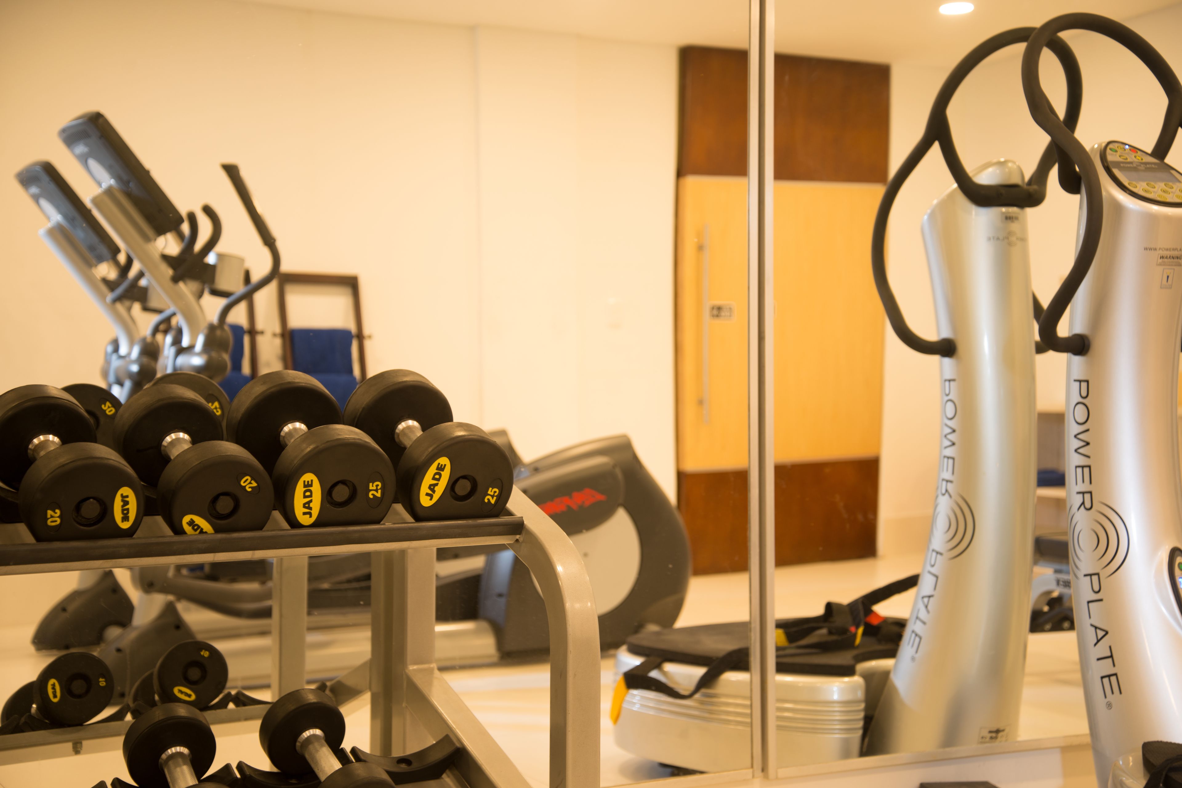 A gym with various exercise equipment including dumbbells, a stationary bike, and a power plate.