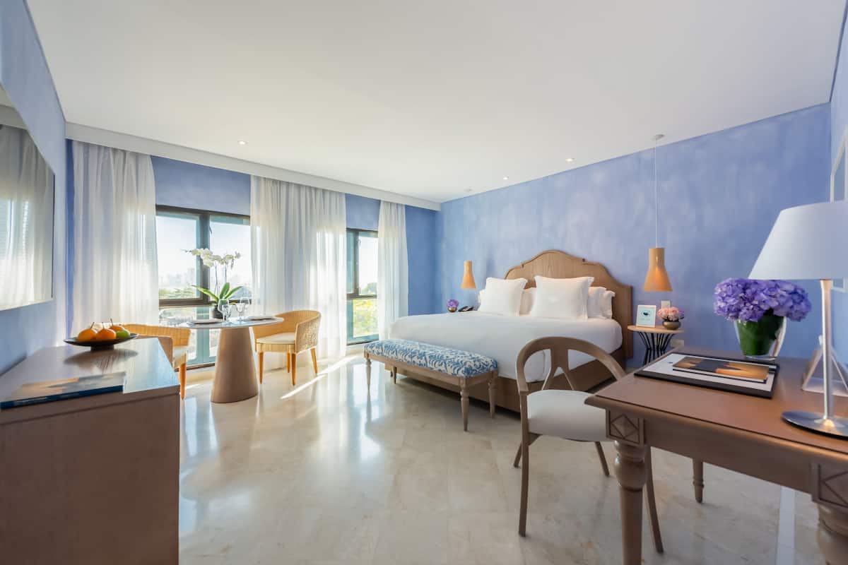 Een moderne hotelkamer met een groot bed, een bureau, een stoel en een zithoek met een tafel en stoelen.