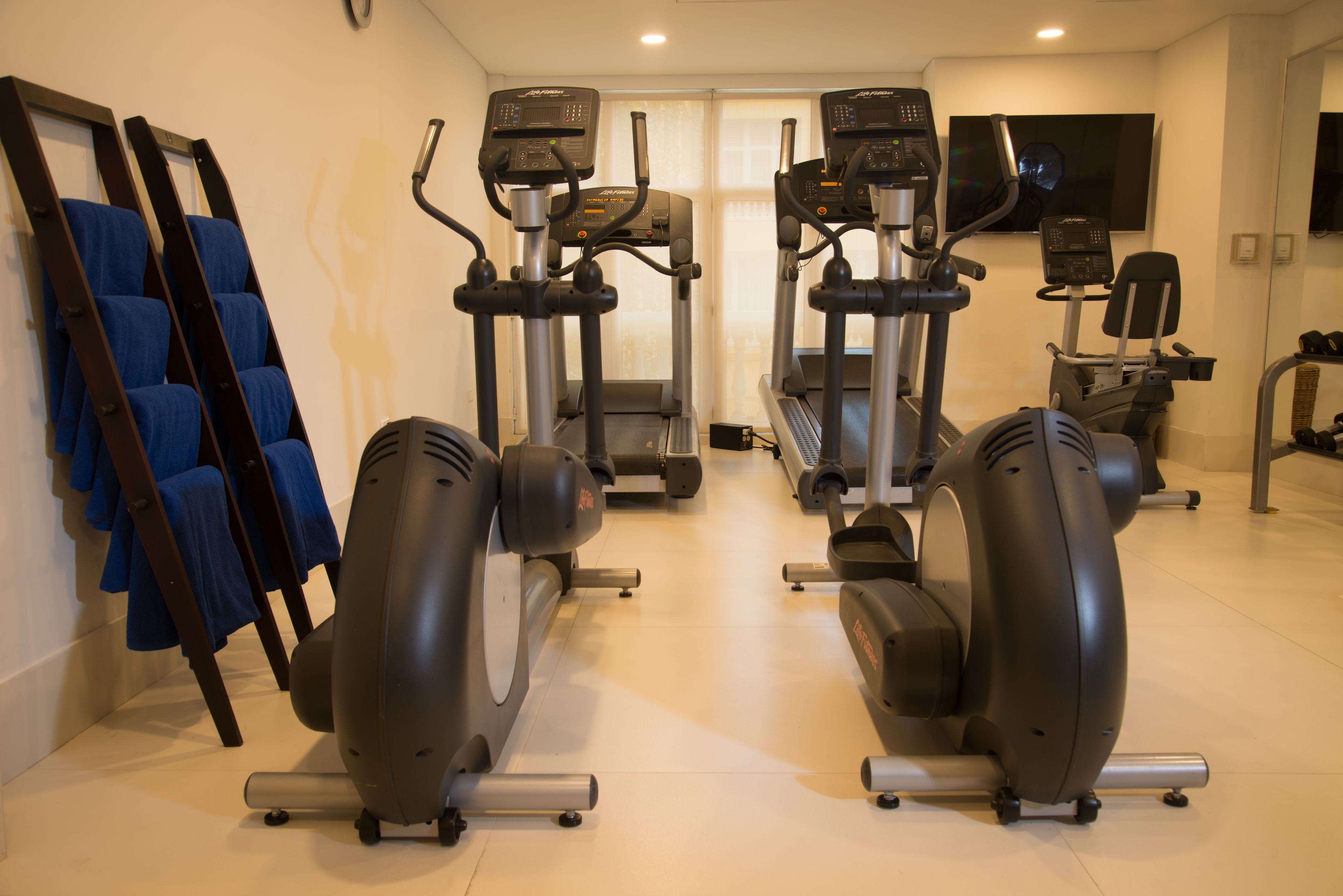 Een fitnessruimte met hometrainers, loopbanden en krachtapparaten.