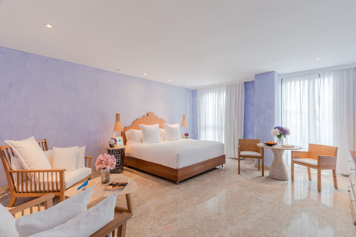 Een hotelkamer met een bed, twee banken, een ronde tafel en een stoel.