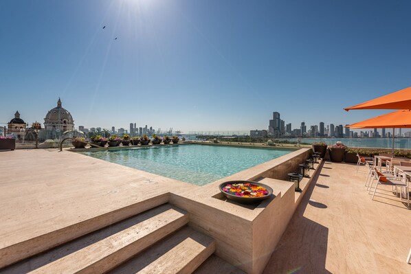 Una piscina al aire libre, sombrillas, sillones reclinables de piscina