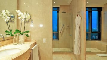 Un baño moderno con un espejo grande, orquídeas, un lavabo y una zona de ducha con mampara de vidrio.