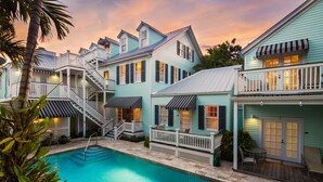 A poolside area with a swimming pool, a staircase leading to a deck, and a building with multiple windows and balconies.