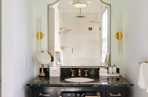 A bathroom with a large mirror, a sink, and a shower area. - The Marquesa Hotel (Key West)