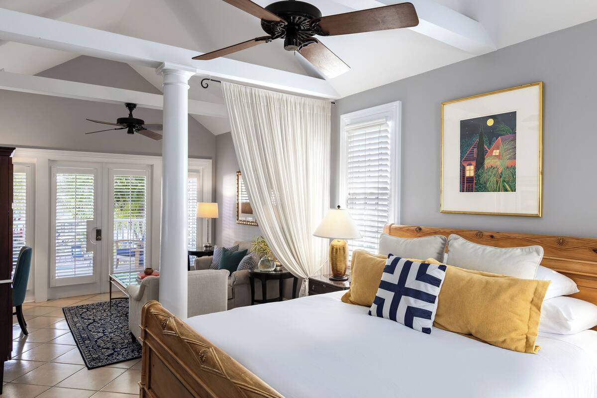 A hotel room with a bed, a ceiling fan, a nightlight, and a framed picture on the wall.