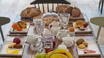 Una mesa de desayuno con pan, pasteles, frutas y bebidas.