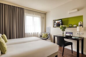 A hotel room with two beds, a desk with a laptop, a chair, a TV, and a vase with flowers. - Citadines Sainte-Catherine Brussels (Brussels)