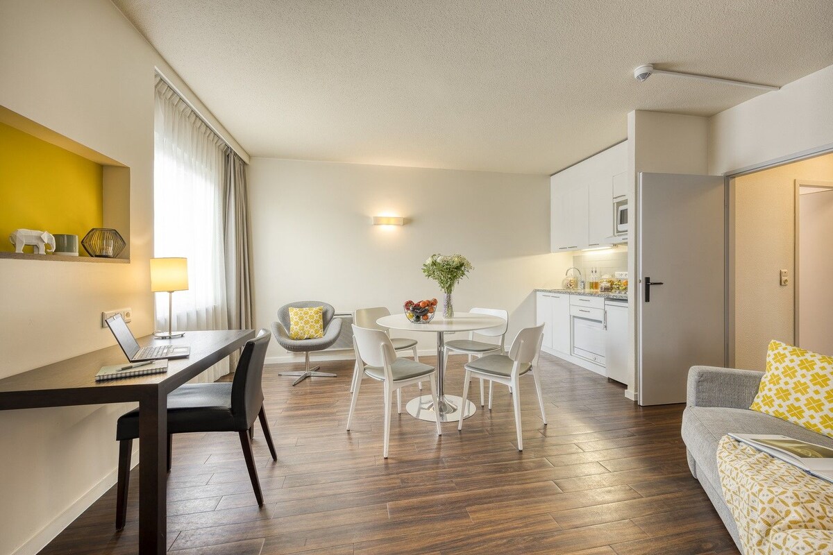 A modern, well-lit living room with a dining area, a kitchen, and a cozy seating area.
