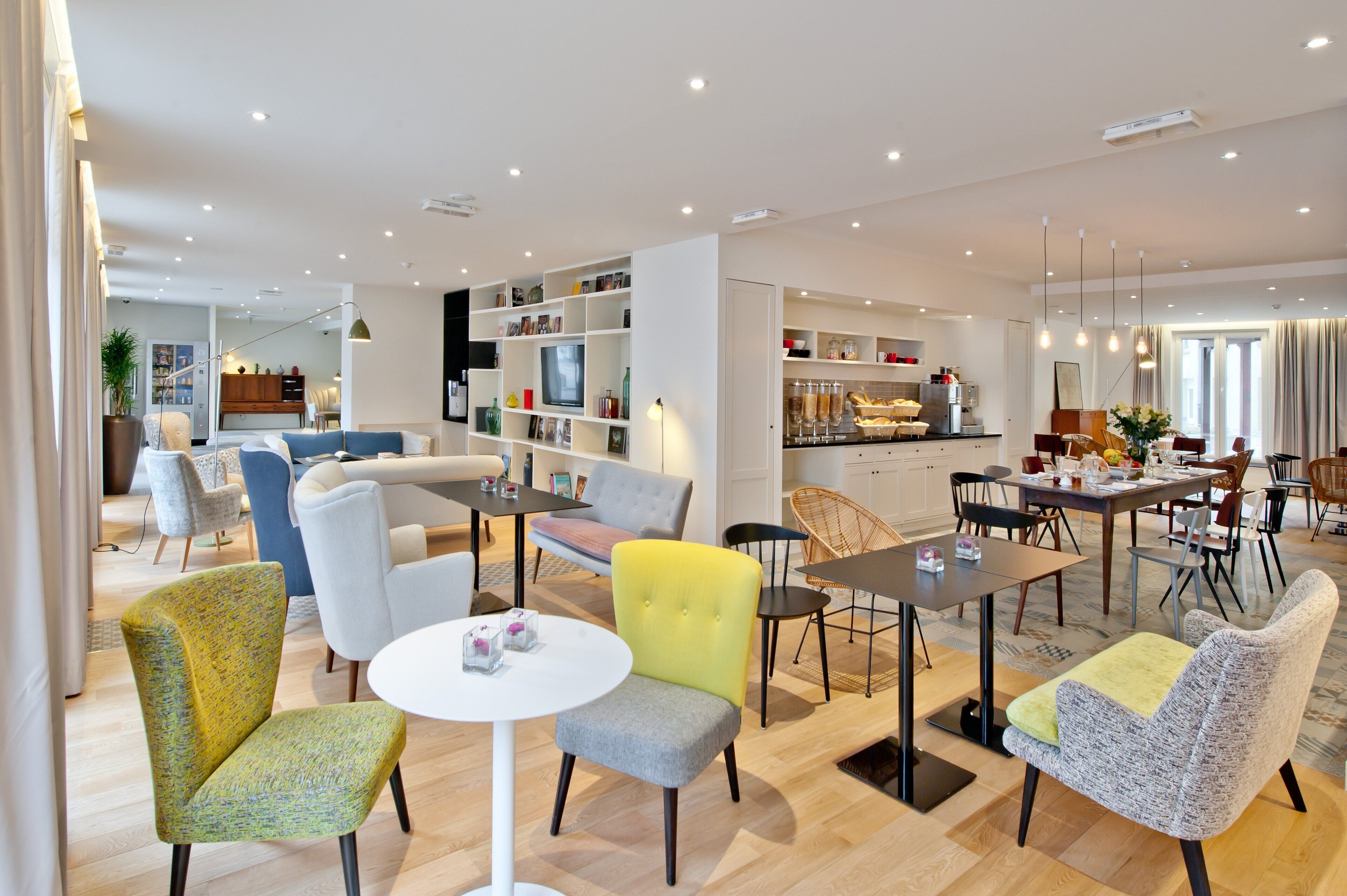 Een moderne woonkamer met een eethoek, met een bank, stoelen, een salontafel en een keuken op de achtergrond.