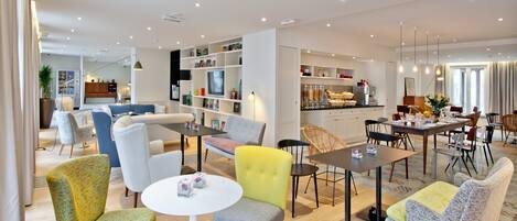 Una sala de estar moderna con comedor, que incluye un sofá, sillas, una mesita de centro y una cocina al fondo.