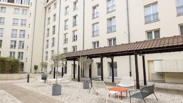 A courtyard with outdoor seating, potted plants, and a building with multiple balconies.