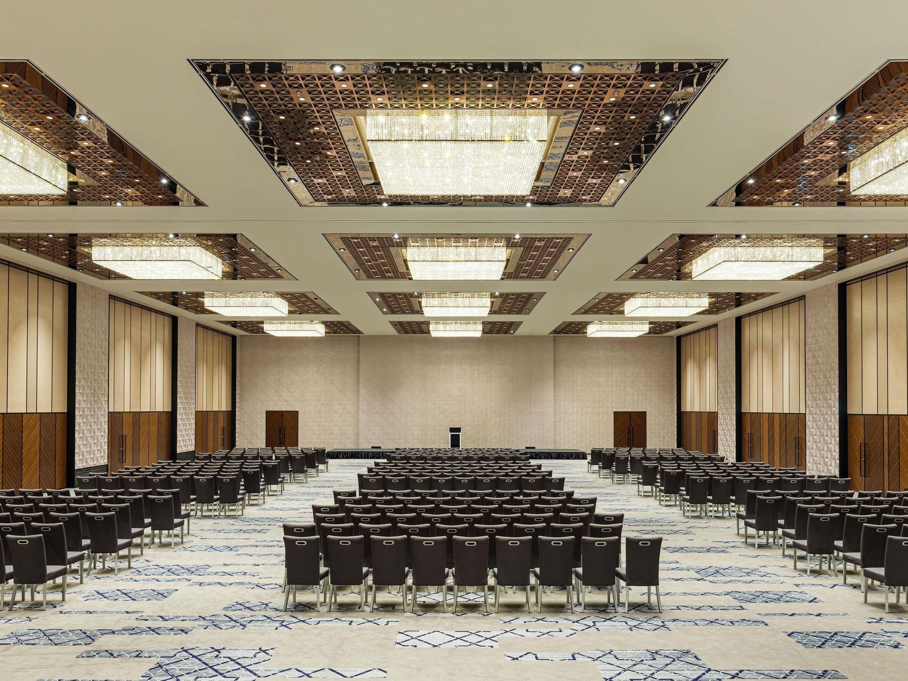A large conference room with rows of chairs, a patterned carpet, and a high ceiling with recessed lighting.