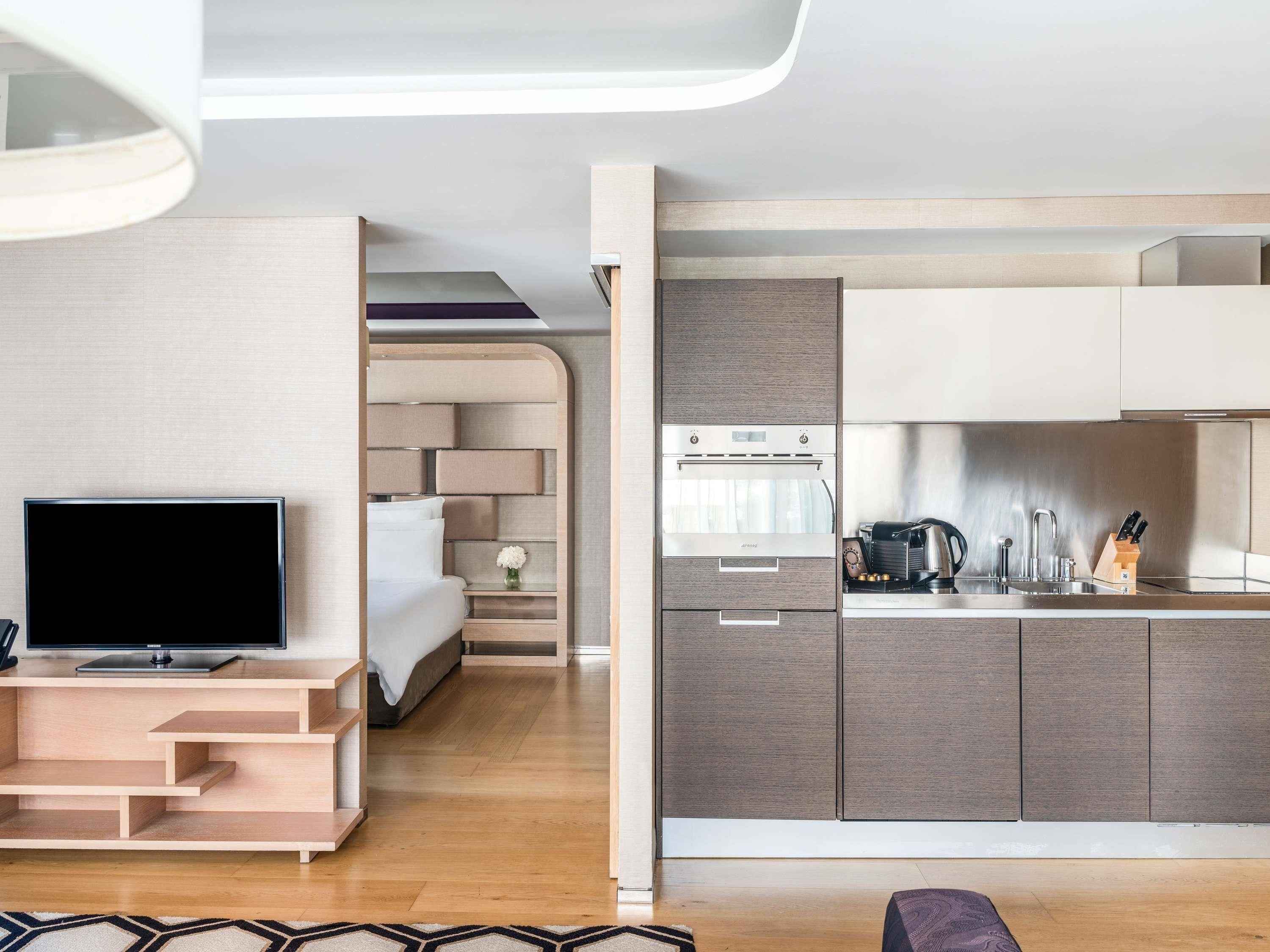 Un espacio habitable moderno con una televisión de pantalla plana, un sofá, una cocina con estufa y una mesa de comedor.