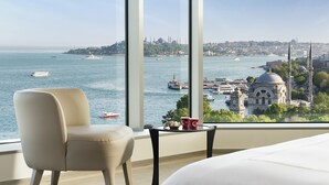 A hotel room with a large window offering a view of a cityscape, including a prominent mosque and a body of water with boats. - Swissotel The Bosphorus Istanbul (Istanbul)