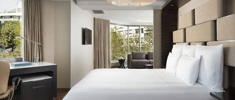 A modern hotel room with a large bed, a desk, and a view of the city.
