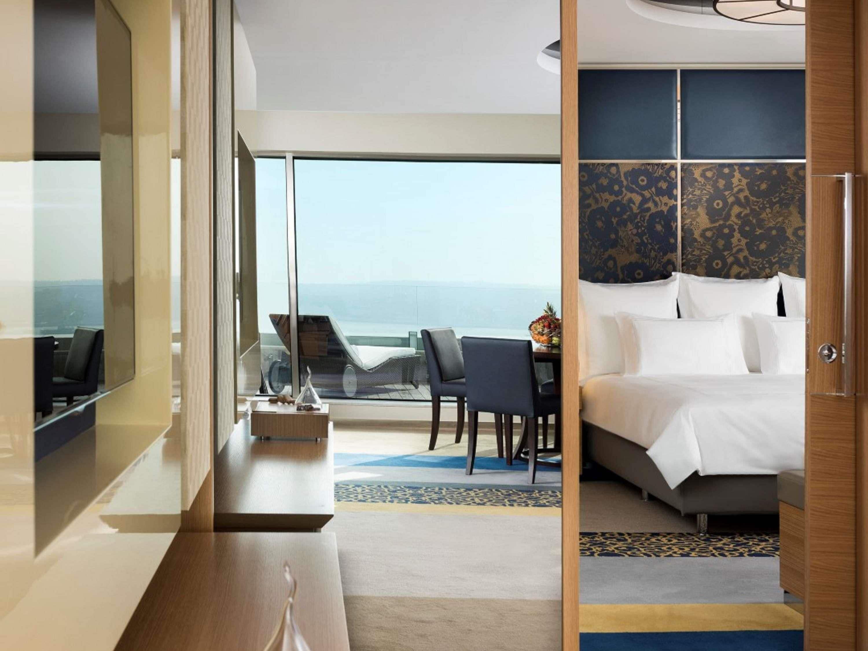 A hotel room with a bed, a desk, and a view of the ocean.