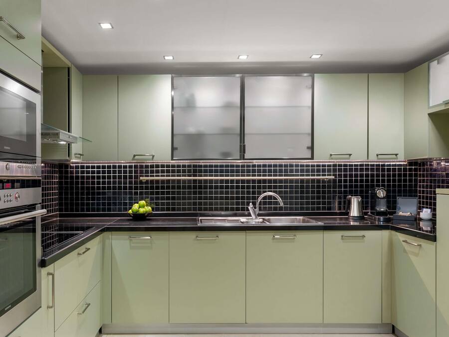 A modern kitchen with a stainless steel range hood, a black tiled backsplash, and a single-bowl fruit bowl.