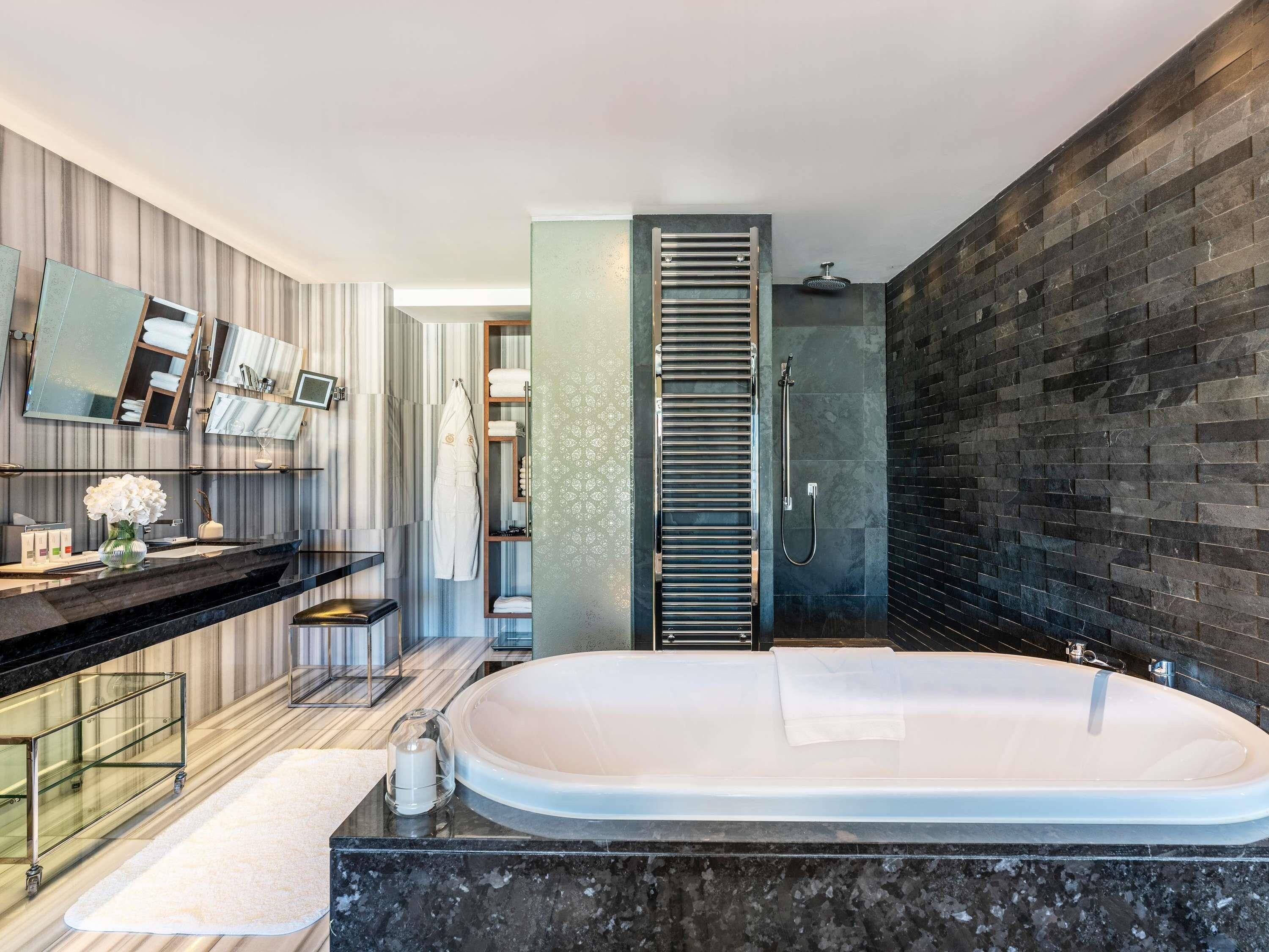 A modern bathroom with a large bathtub, a vanity with a mirror, and a shower area.