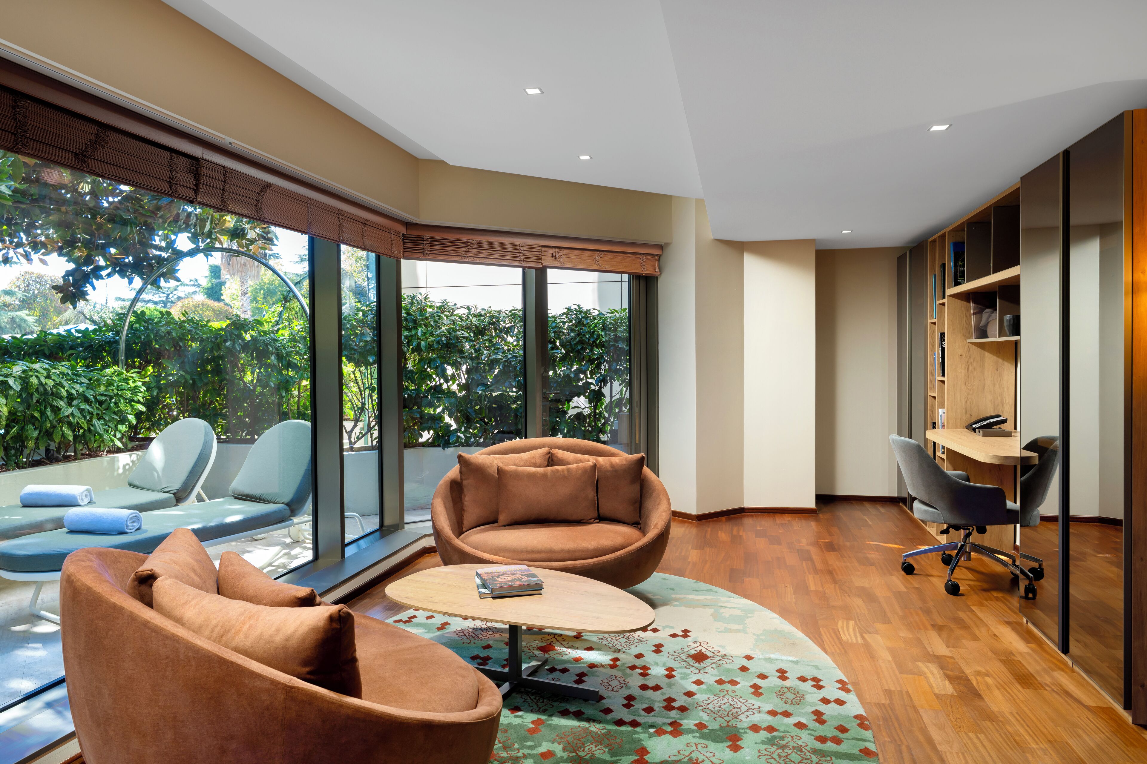 Una sala de estar moderna con un sofá, sillones, una mesa de centro y una zona de escritorio.