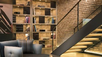 Un interior moderno con pared de ladrillo, una escalera y una estantería llena de libros.